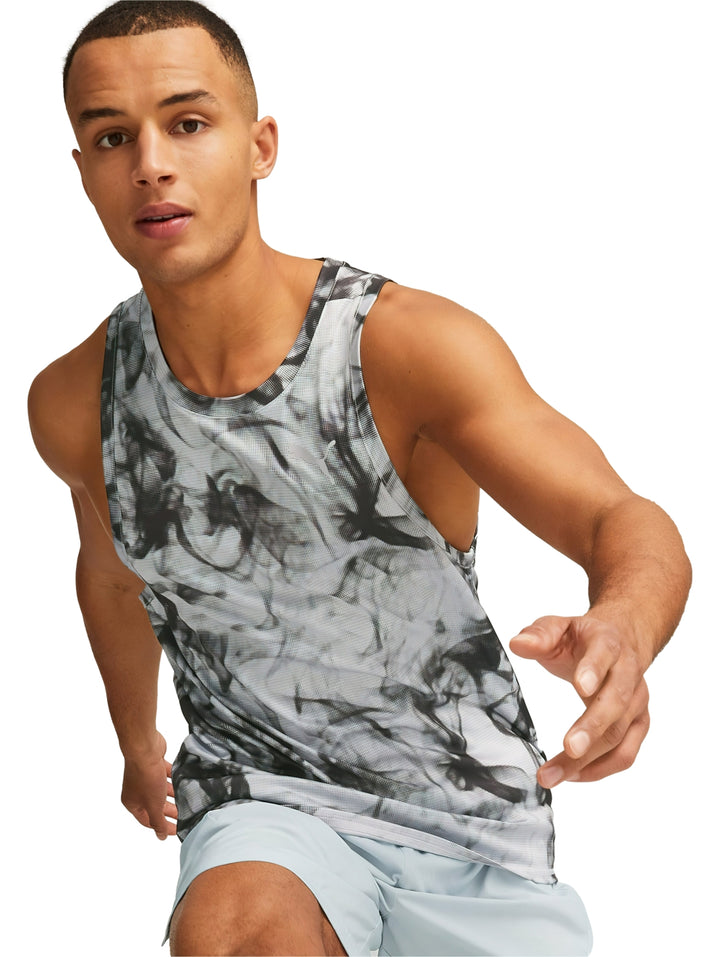 Hombre vistiendo camiseta deportiva sin mangas PUMA en color gris platino con estampado abstracto.