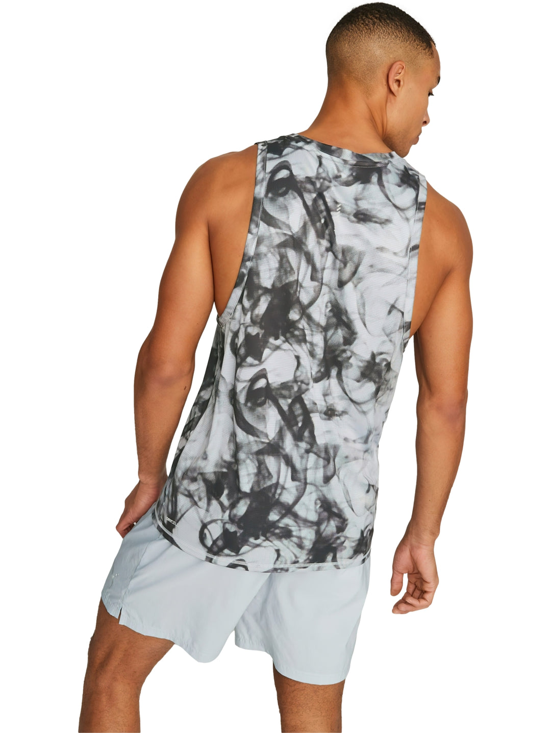 Hombre vistiendo camiseta deportiva sin mangas PUMA en color gris platino con estampado abstracto.