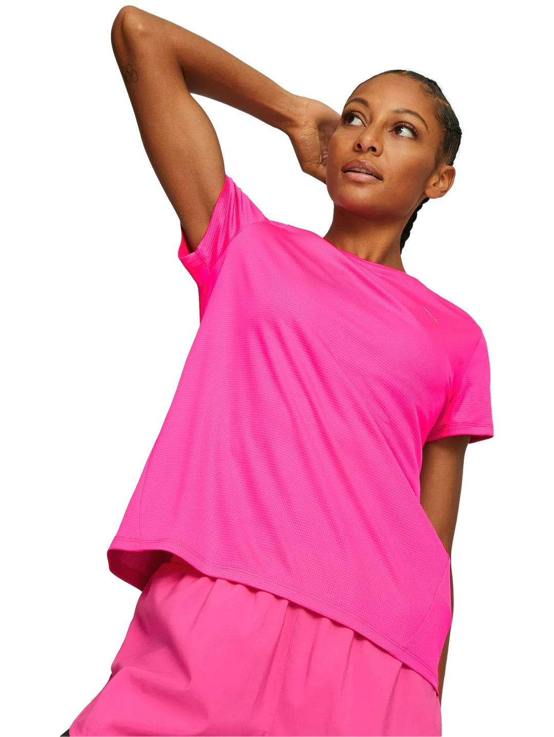 Mujer vistiendo camiseta deportiva PUMA de color rosa brillante y pantalones a juego.
