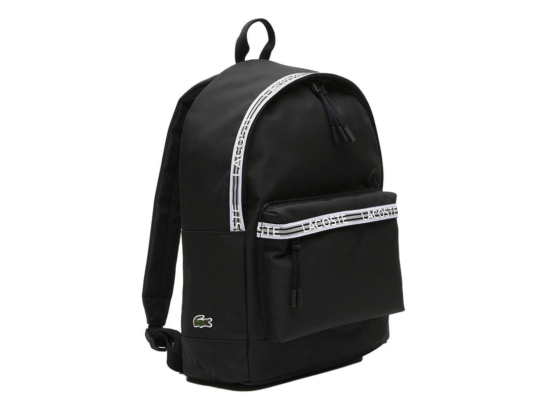 Mochila Lacoste color negro con una banda horizontal blanca decorativa en el bolsillo frontal.