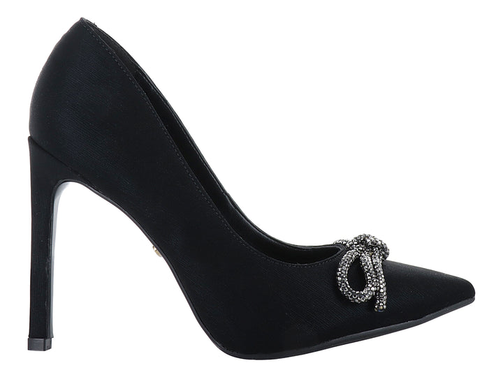 Zapato de tacón alto color negro con un moño decorativo de cristales plateados en la punta.