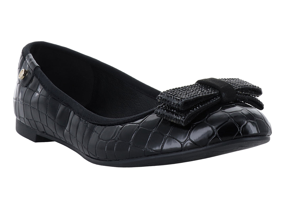 Zapato plano negro con textura de cocodrilo y moño decorativo frontal.