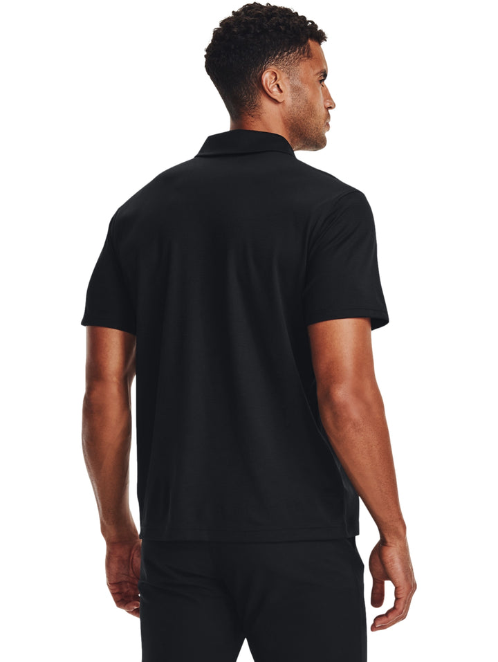 Hombre vistiendo una playera polo Under Armour de color negro, estilo deportivo y manga corta.