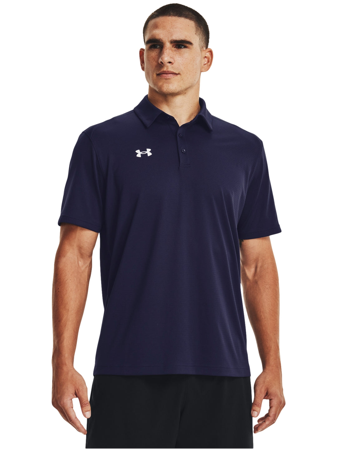 Hombre vistiendo polo deportivo Under Armour de color azul marino con logotipo blanco en el pecho.
