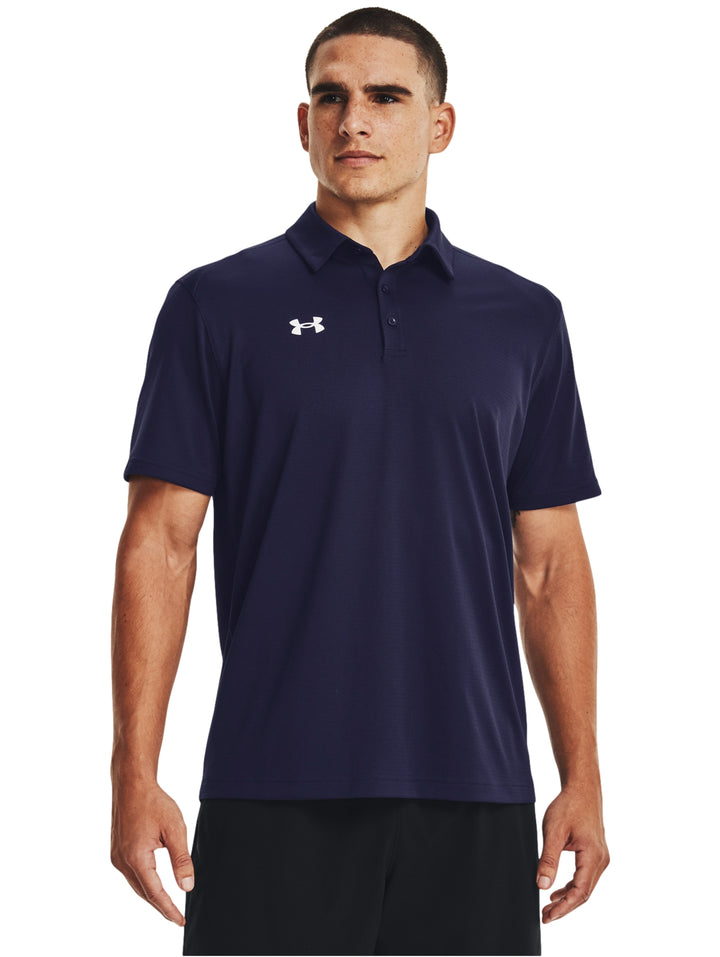 Hombre vistiendo polo deportivo Under Armour de color azul marino con logotipo blanco en el pecho.