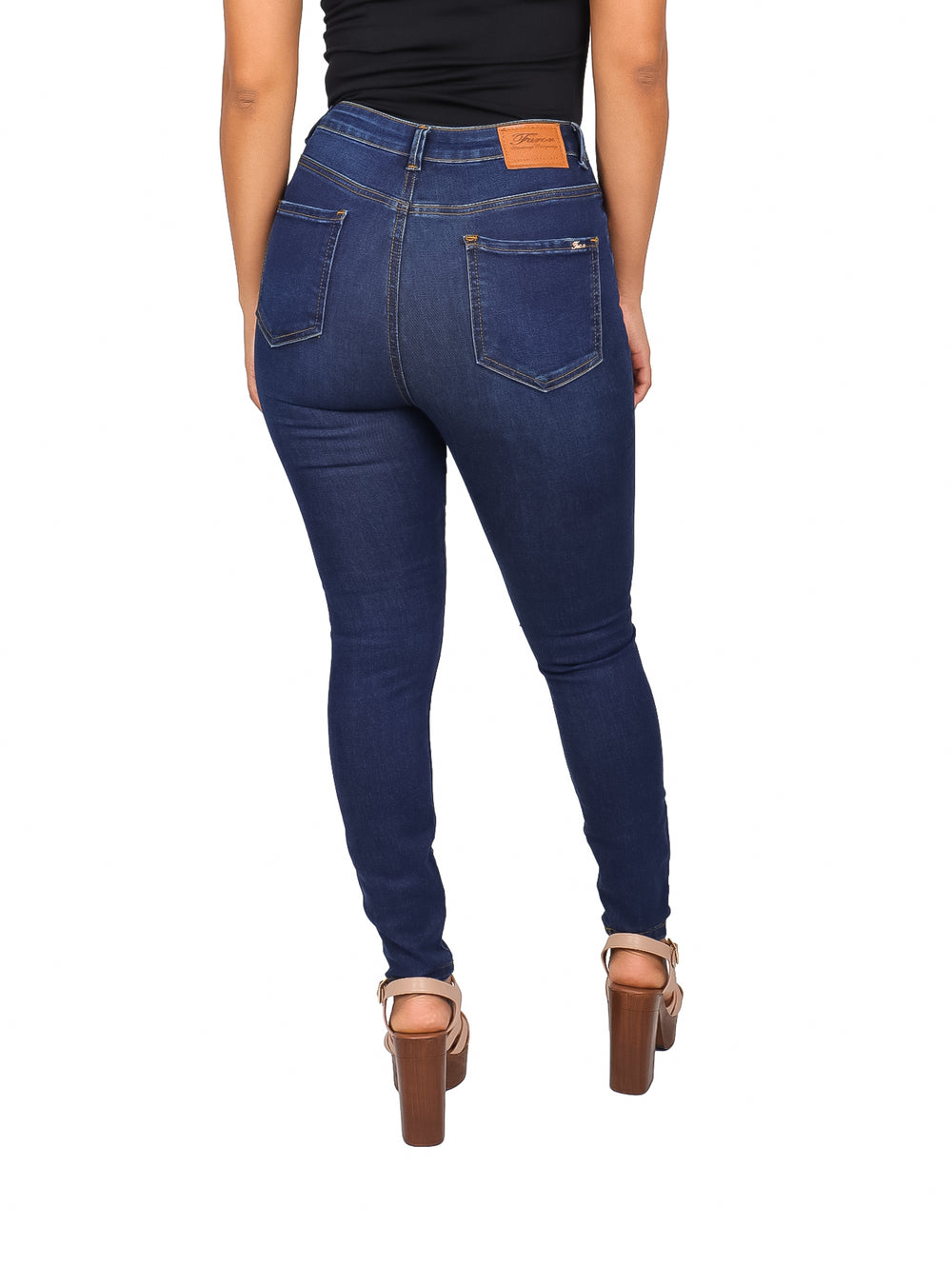 Mujer vistiendo pantalón jeans ajustado color azul oscuro con detalles de destrucción en las rodillas.
