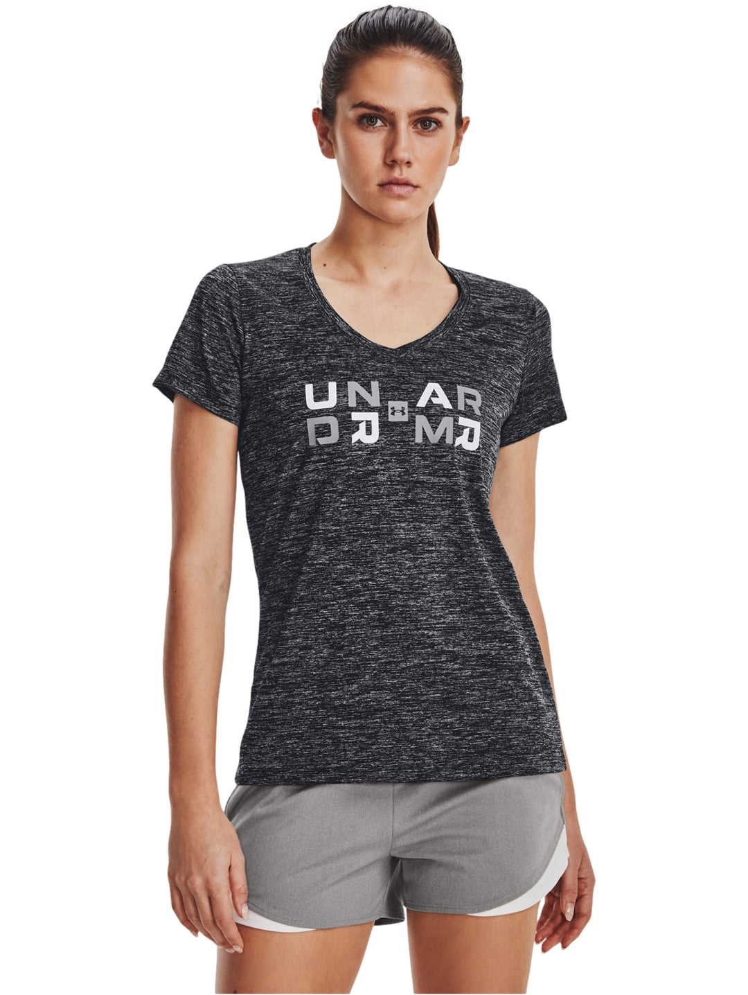 Mujer vistiendo playera deportiva Under Armour color negro jaspeado con gráfico blanco y shorts grises.