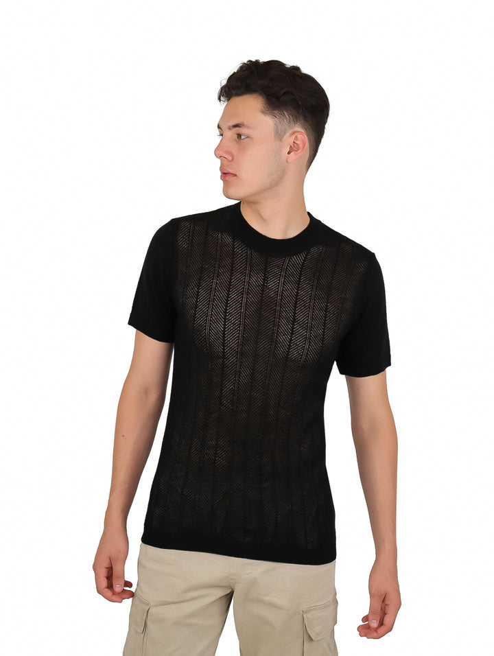Hombre vistiendo una playera negra de manga corta con textura acanalada y pantalones beige.