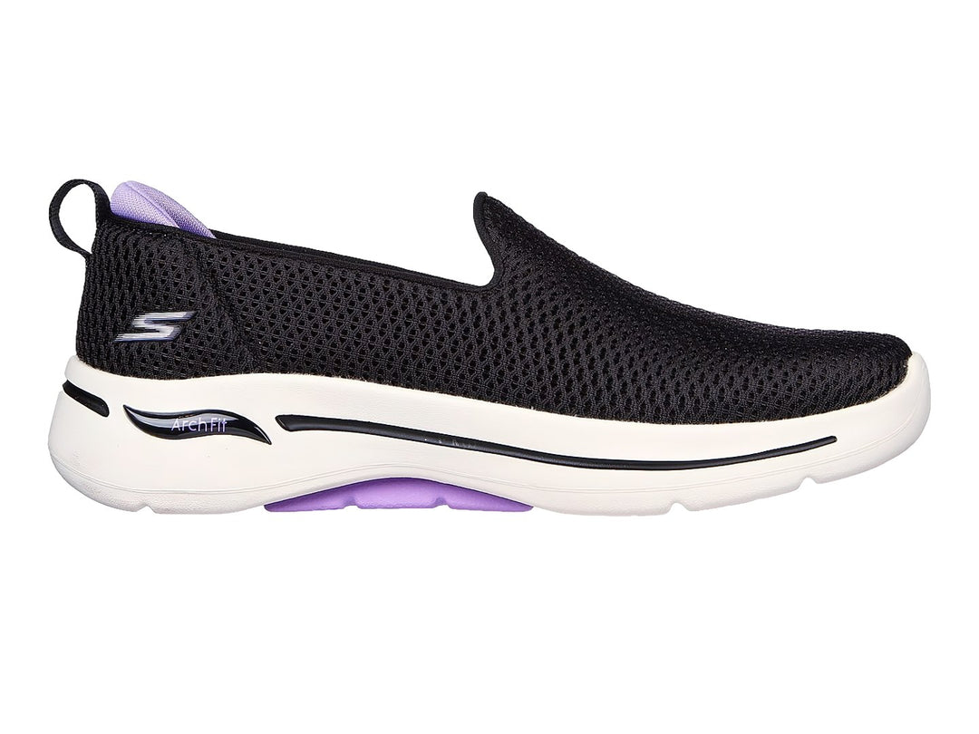 Tenis Skechers negros estilo slip-on con suela blanca y detalles en color lavanda.