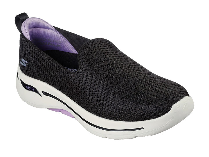 Tenis Skechers negros estilo slip-on con suela blanca y detalles en color lavanda.