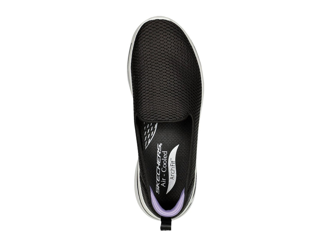 Tenis Skechers negros estilo slip-on con suela blanca y detalles en color lavanda.
