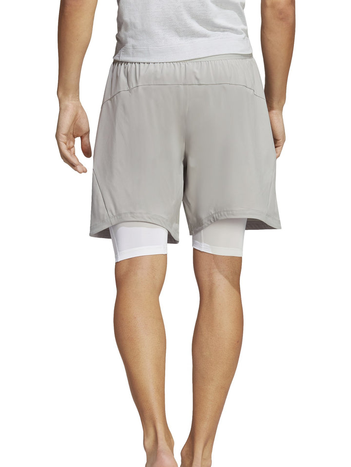 Hombre usando shorts de yoga 2 en 1 color gris de Adidas.