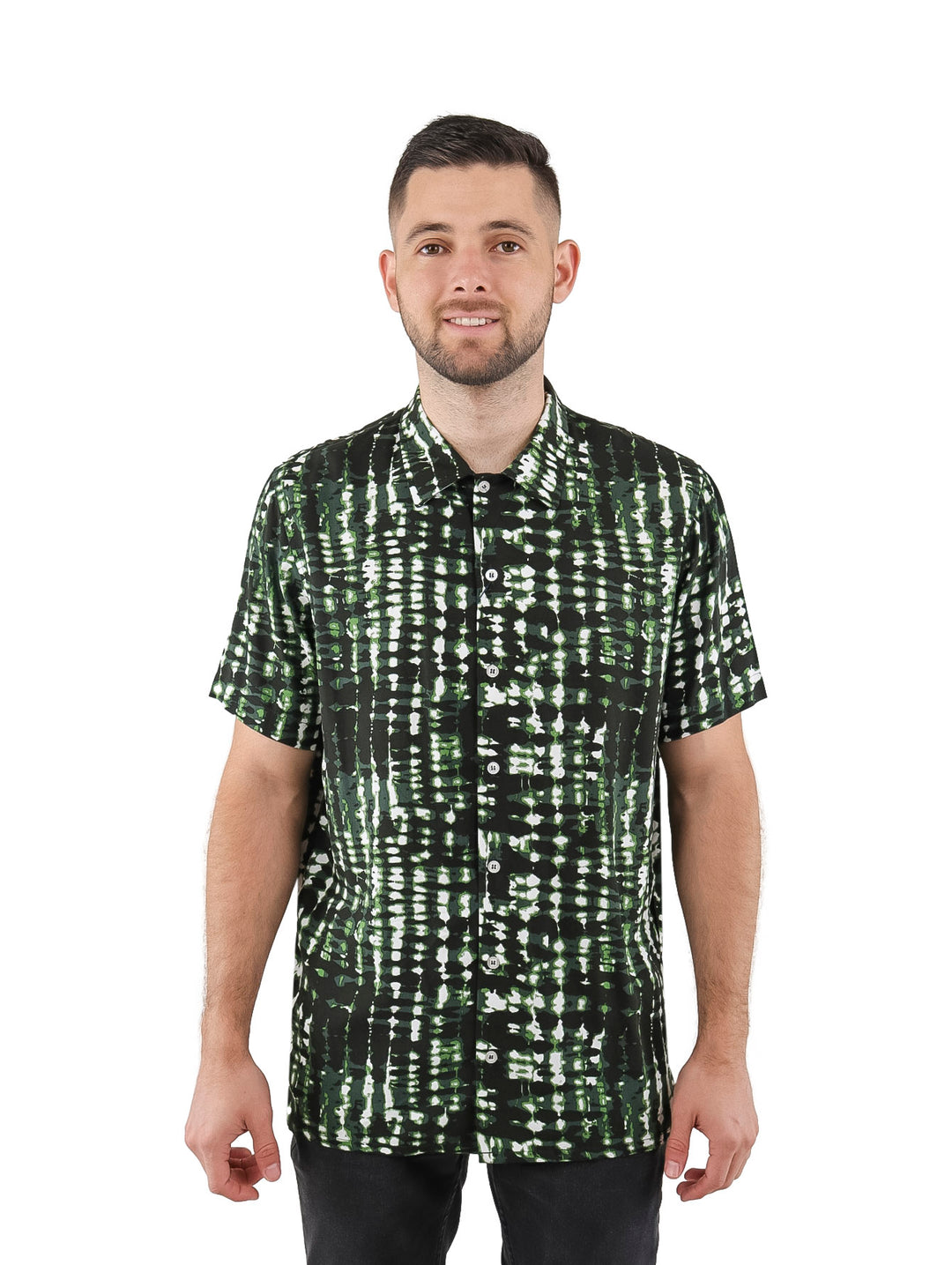 Hombre vistiendo camisa de manga corta con estampado abstracto en tonos verde, negro y blanco.