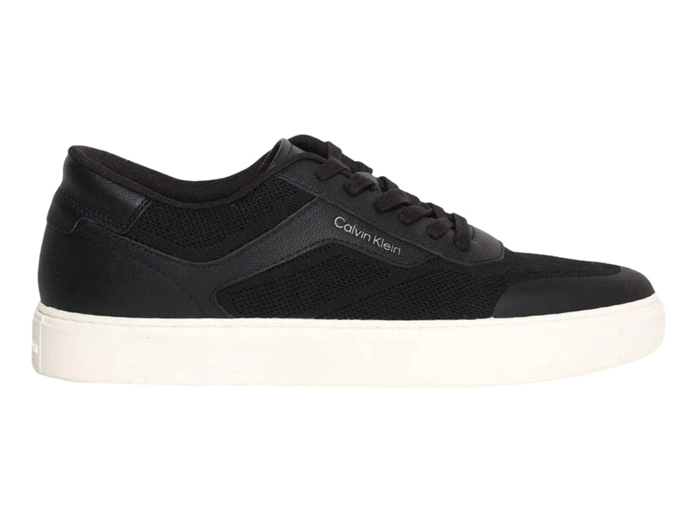 Tenis Calvin Klein negros de corte bajo con suela blanca y detalles en tejido.