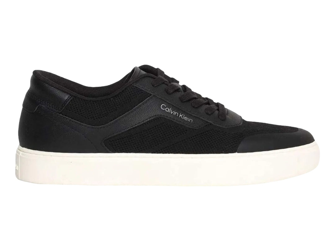 Tenis Calvin Klein negros de corte bajo con suela blanca y detalles en tejido.