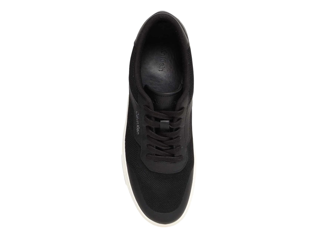 Tenis Calvin Klein negros de corte bajo con suela blanca y detalles en tejido.