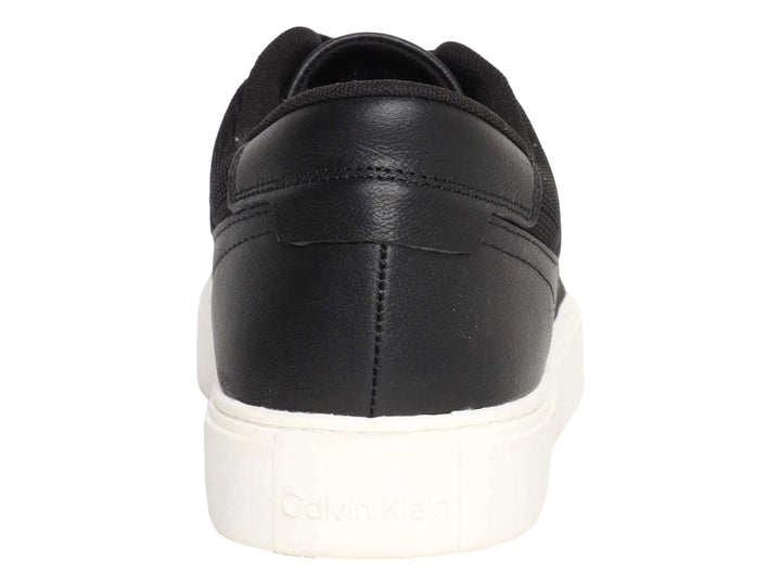 Tenis Calvin Klein negros de corte bajo con suela blanca y detalles en tejido.