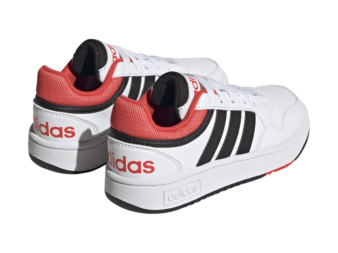 Tenis Adidas Hoops 3.0 en color blanco con franjas negras y detalles en rojo, diseño deportivo para niños.