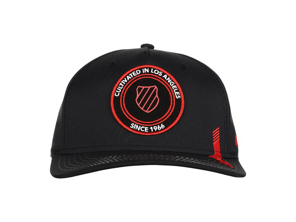 Gorra K-Swiss color negro con logotipo circular bordado en rojo en el frente y detalle lateral rojo.