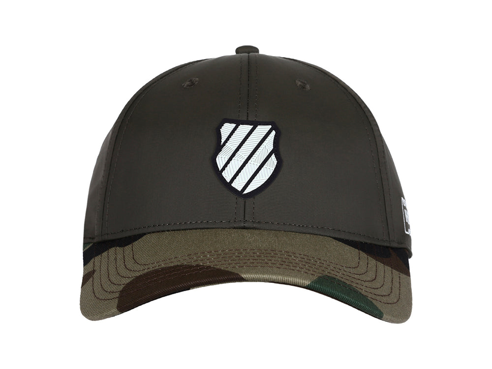 Gorra K-Swiss color olivo con visera en estampado de camuflaje y logo blanco frontal.