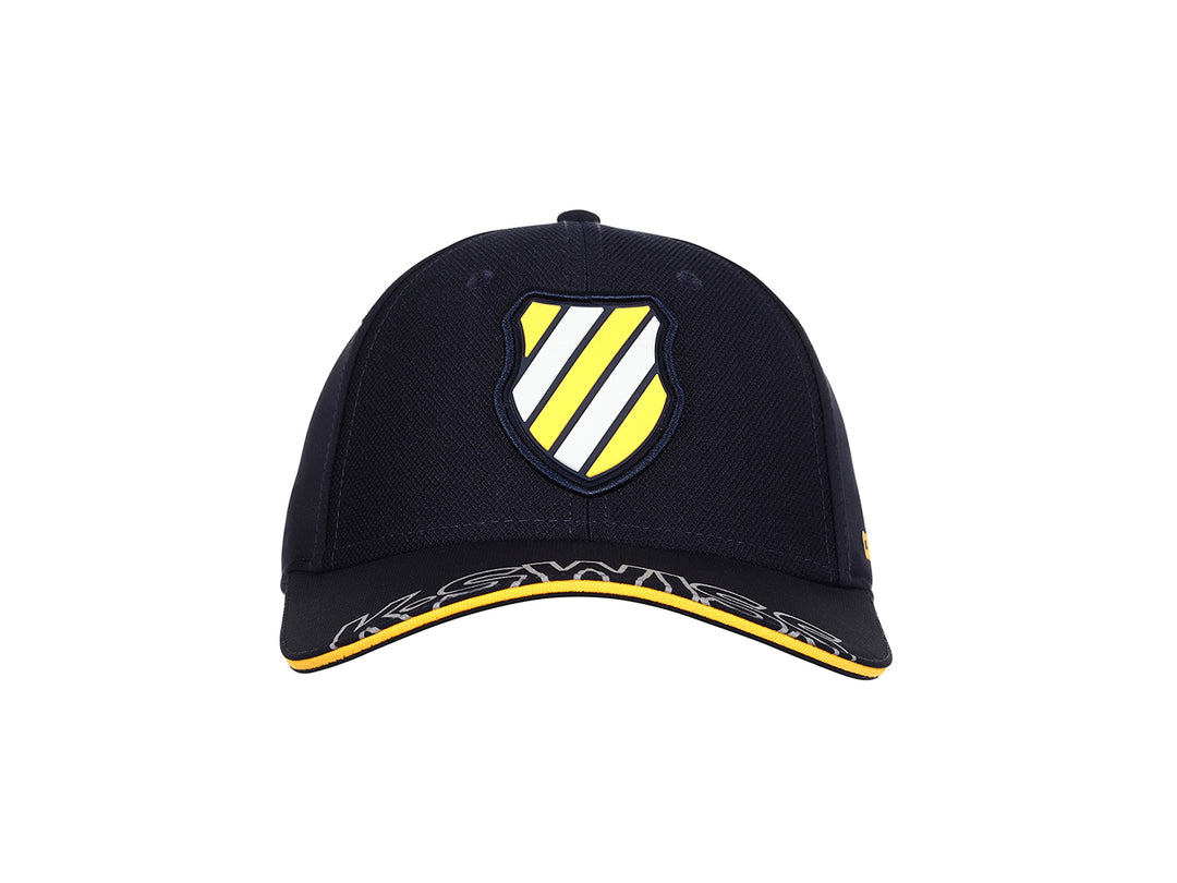 Gorra K-Swiss color marino con visera curva, detalles en amarillo y logotipo frontal.