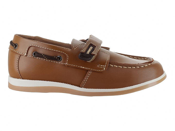 Zapato tipo mocasín color camel para niño con correa de ajuste y suela blanca.