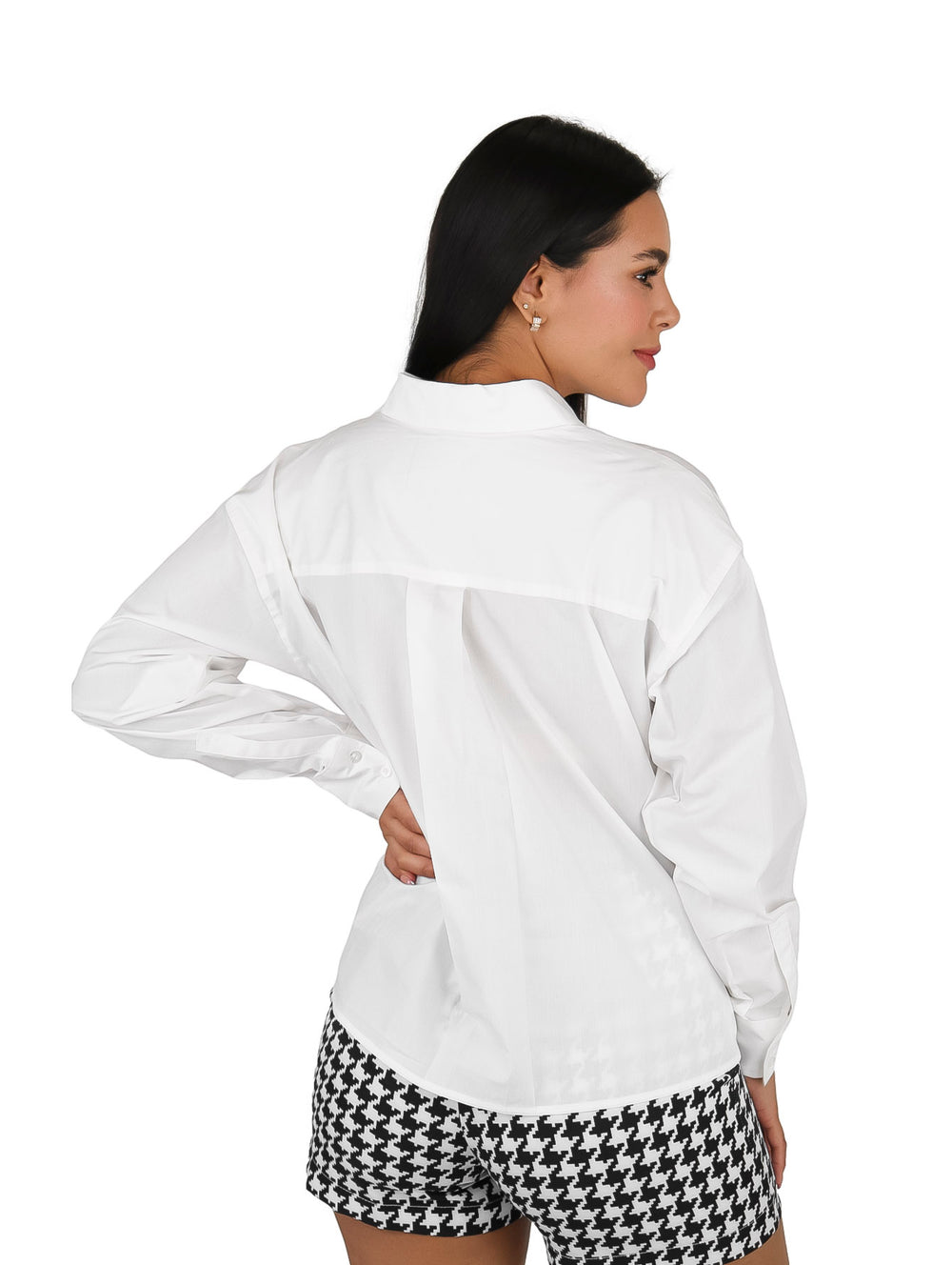 Mujer vistiendo una camisa blanca de manga larga con cuello y un bolsillo frontal.