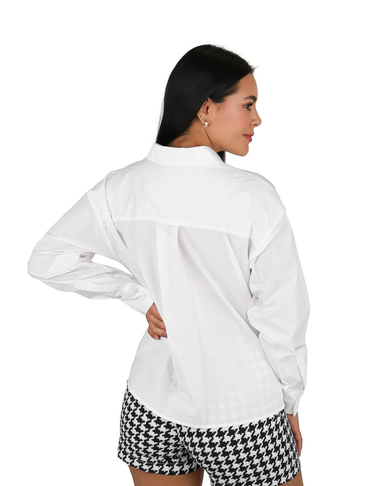 Mujer vistiendo una camisa blanca de manga larga con cuello y un bolsillo frontal.