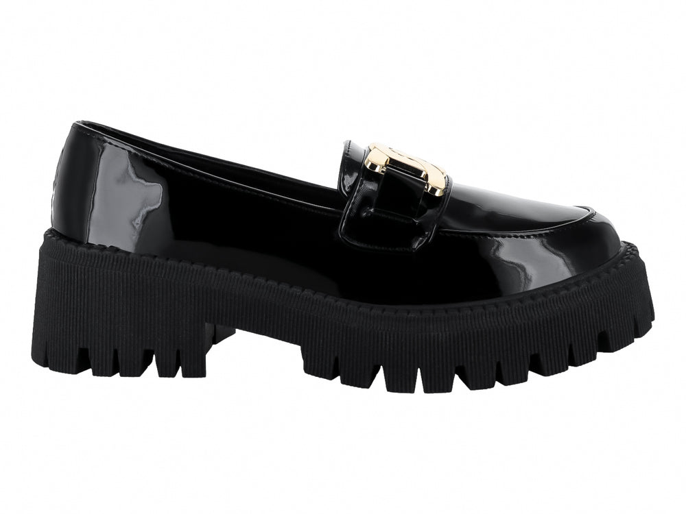 Zapato mocasín de charol negro con hebilla dorada y suela de plataforma gruesa dentada.