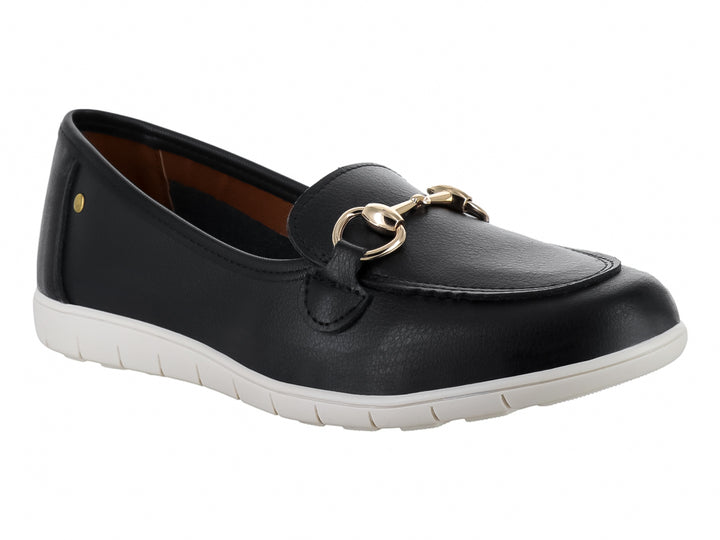 Zapato plano tipo mocasín color negro con suela blanca y detalle metálico dorado en la parte superior.