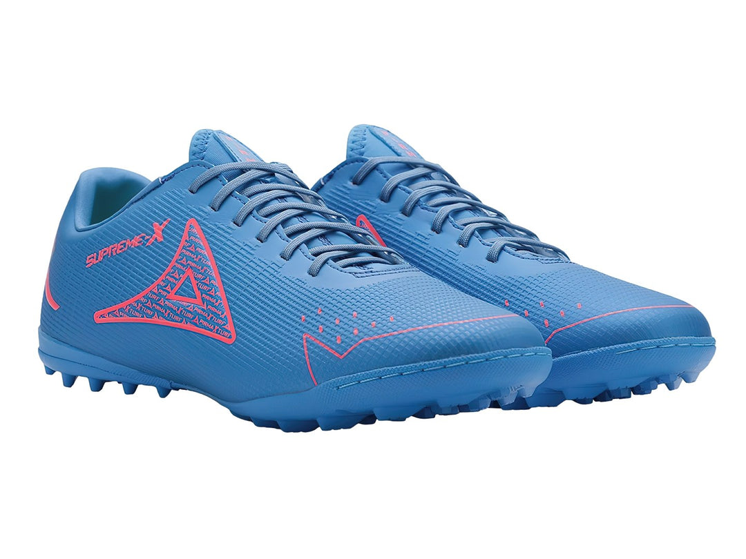 Par de zapatos de fútbol Pirma Brasil en color azul con detalles en carmín y suela para césped sintético.