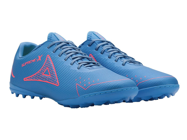 Par de zapatos de fútbol Pirma Brasil en color azul con detalles en carmín y suela para césped sintético.