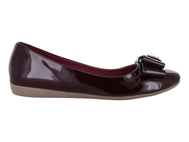 Zapato plano color vino en acabado charol brillante con detalle de moño decorativo en la parte frontal.