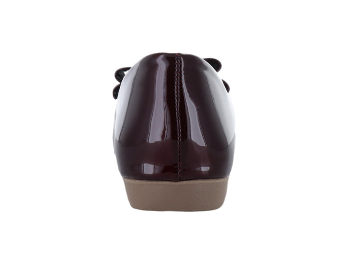 Zapato plano color vino en acabado charol brillante con detalle de moño decorativo en la parte frontal.