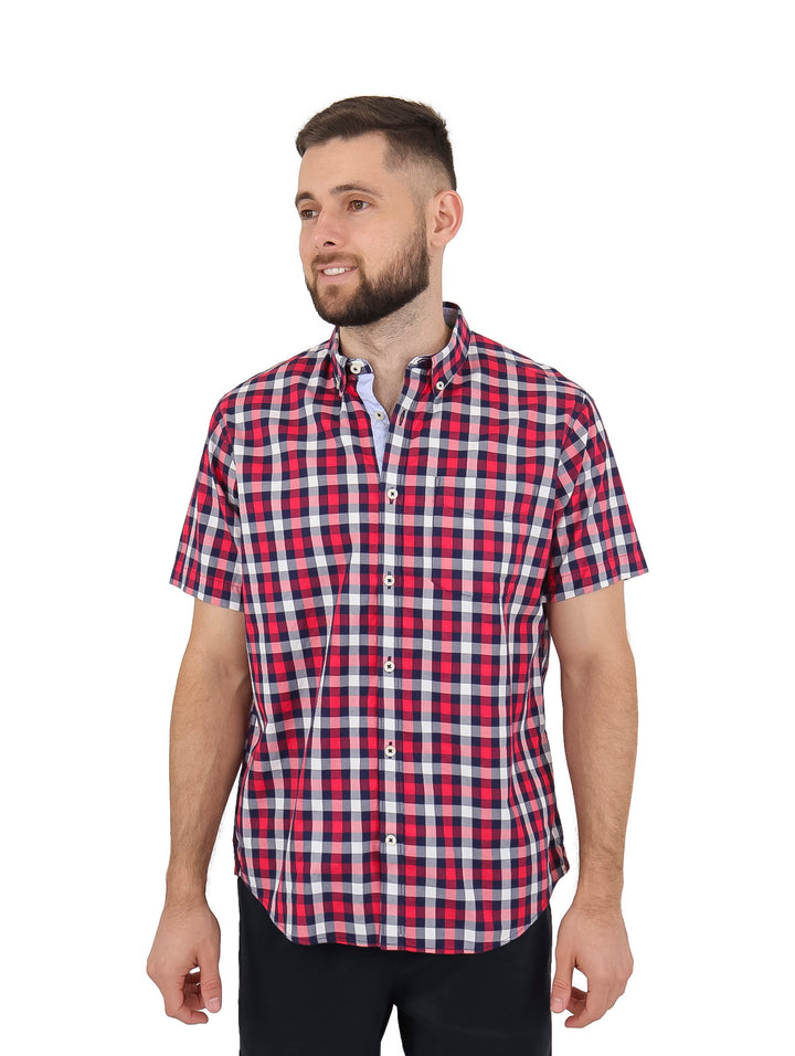 Hombre vistiendo una camisa casual de manga corta con estampado de cuadros en colores rojo, blanco y azul marino.