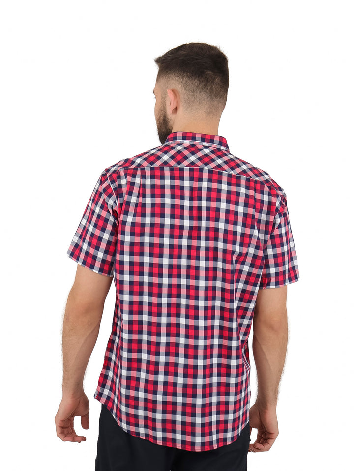 Hombre vistiendo una camisa casual de manga corta con estampado de cuadros en colores rojo, blanco y azul marino.
