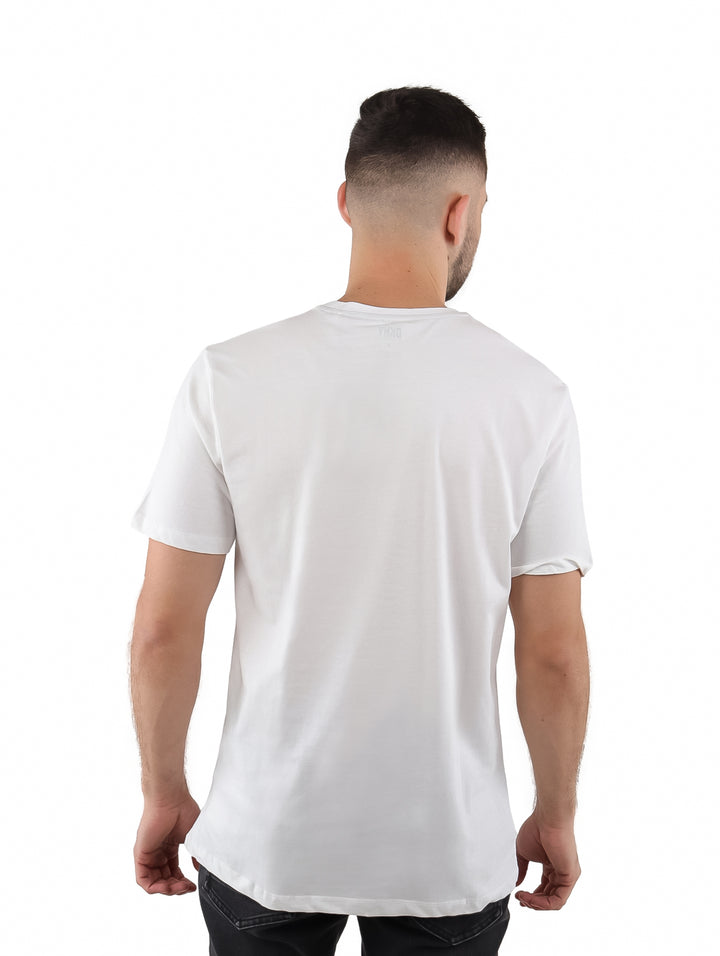 Hombre vistiendo playera blanca de manga corta marca DKNY con estampado gráfico frontal en rojo y negro.