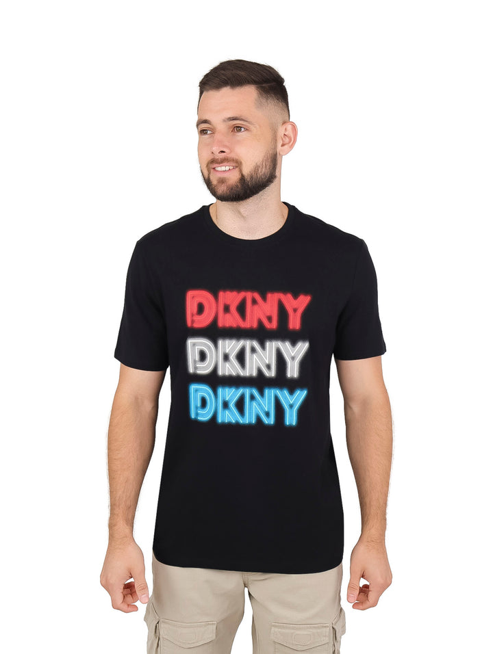 Hombre vistiendo playera negra de manga corta con logotipo DKNY estampado en colores rojo, blanco y azul.