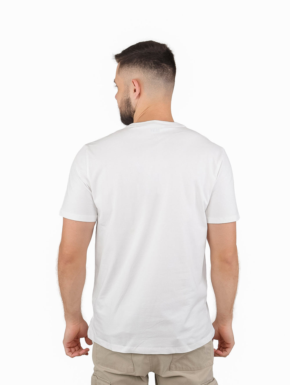 Hombre vistiendo playera blanca de manga corta con diseño de líneas negras y rojas y logo DKNY.