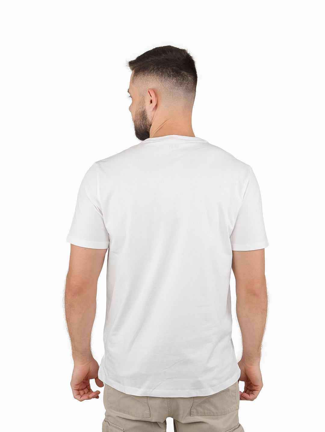 Hombre vistiendo playera blanca de manga corta con diseño de líneas negras y rojas y logo DKNY.