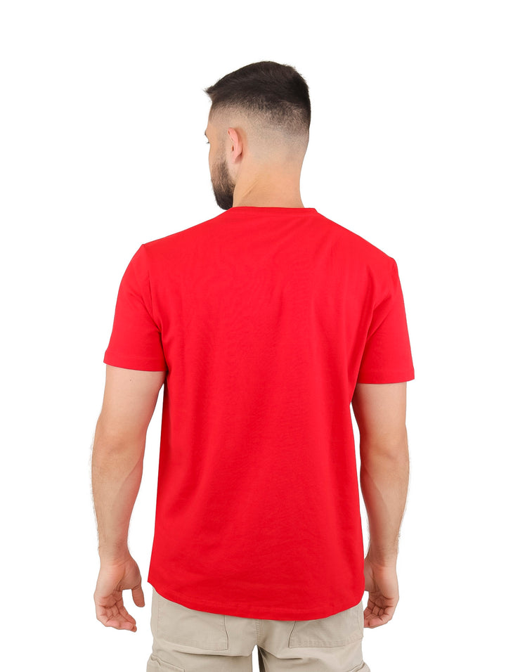 Hombre vistiendo playera roja de manga corta con estampado frontal blanco y gris de la marca DKNY.