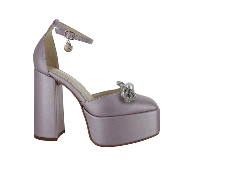 Zapato de tacón plataforma color rosa con detalle de moño plateado y perla blanca.