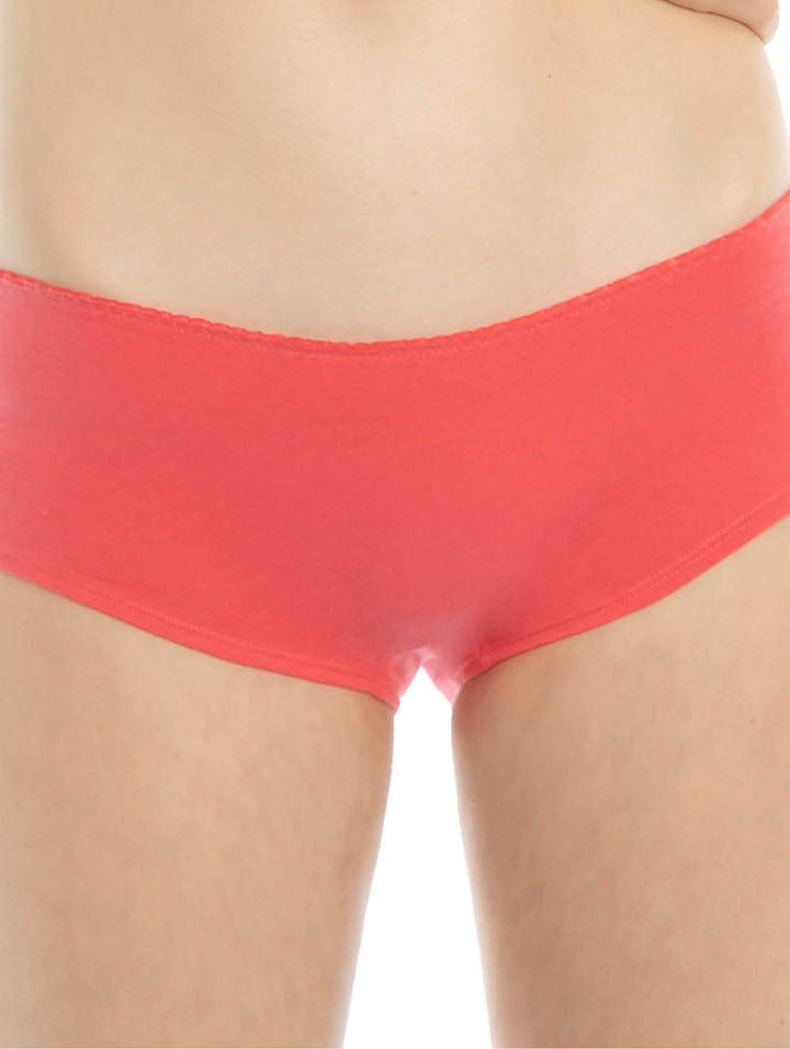 Set de tres boxers para mujer: uno coral sólido y dos blancos con estampados de rayos y yin-yang.