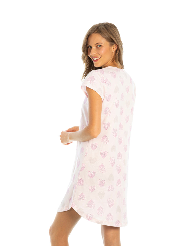 Mujer vistiendo un camisón rosa claro con estampado de corazones y cuello en V.