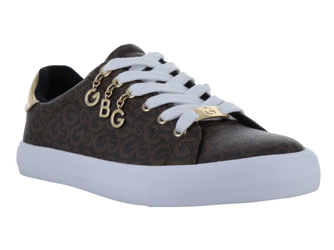Tenis color chocolate con estampado de monograma, suela blanca y adornos dorados en las agujetas.