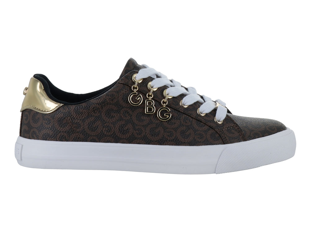 Tenis color chocolate con estampado de monograma, suela blanca y adornos dorados en las agujetas.