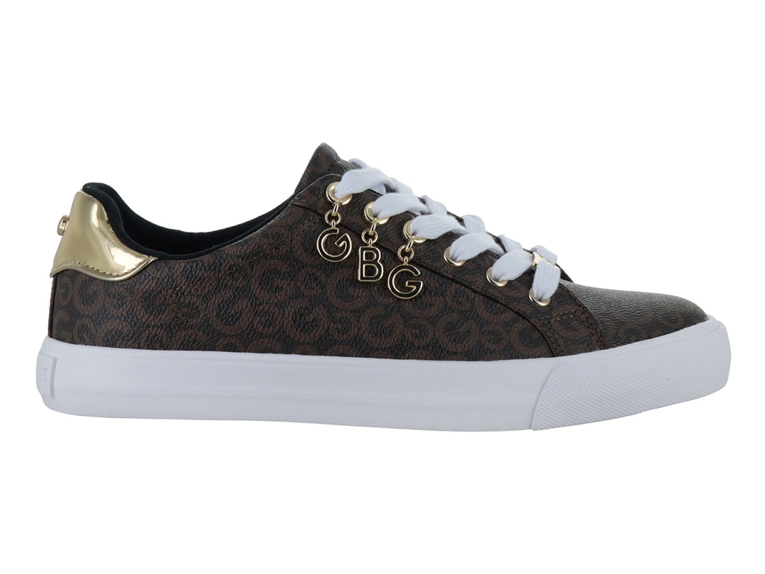 Tenis color chocolate con estampado de monograma, suela blanca y adornos dorados en las agujetas.