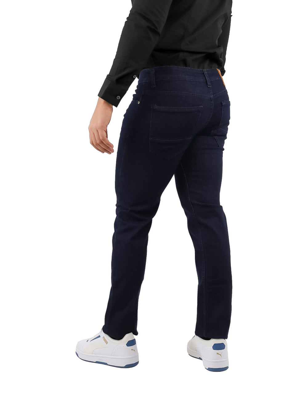 Hombre vistiendo pantalones jeans slim fit color azul petróleo, camisa negra y tenis blancos.