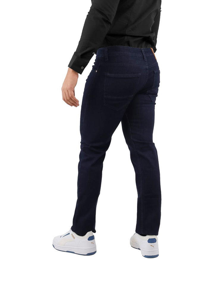 Hombre vistiendo pantalones jeans slim fit color azul petróleo, camisa negra y tenis blancos.