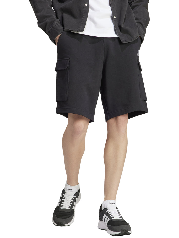 Hombre vistiendo pantalones cortos deportivos color negro de Adidas con bolsillos laterales.